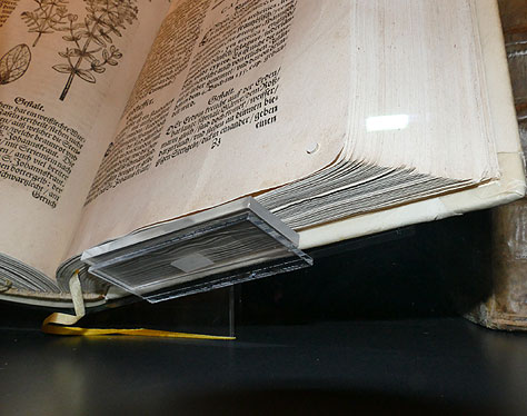 Photo n° 5 : Détail montrant comment la tranche de queue du livre est protégée par une plaquette d'acryl supplémentaire qui comble l'espace vide sous les cahiers.